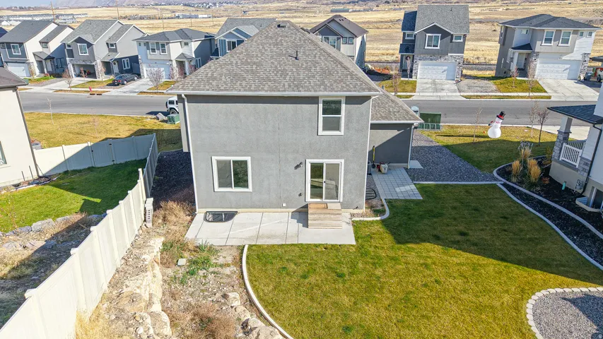 Rear stucco exterior featuring a patio with pavers, a sliding glass door, a fenced perimeter, and an upper-level window