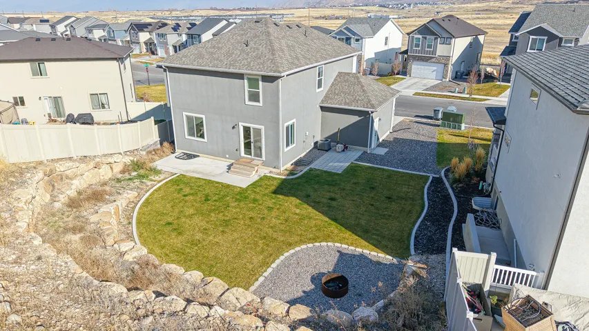 Rear exterior featuring a grey facade, concrete patio, and a manicured lawn
