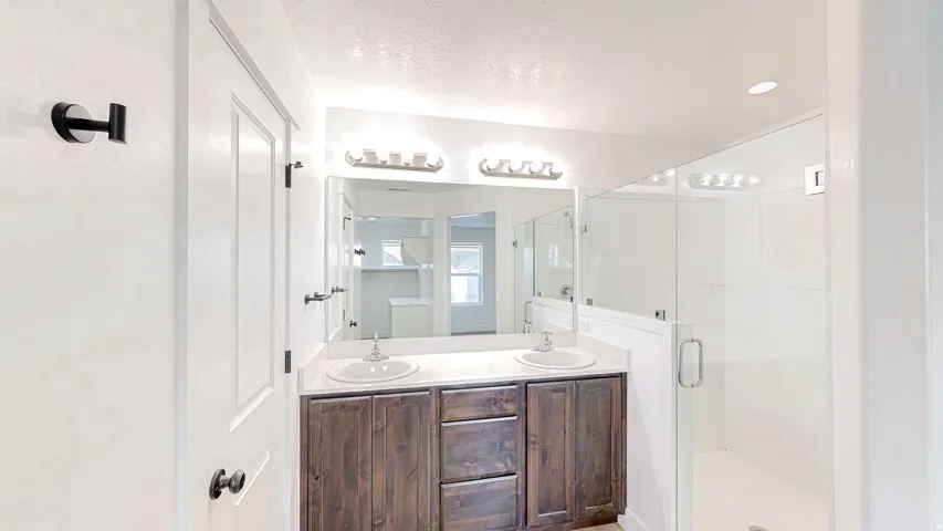 Bathroom featuring a dual-sink vanity with a dark wood-finish cabinet, light countertop, and wall-mounted mirror