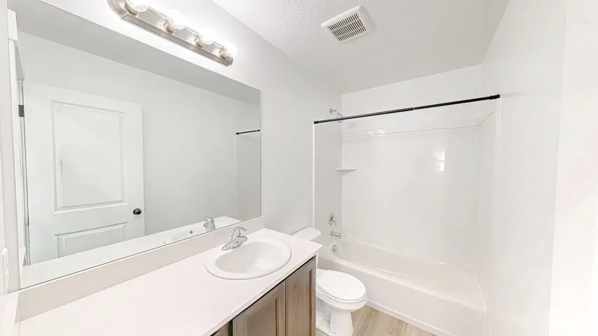 Bathroom featuring a single vanity with integrated sink, a large mirror, and a full bathtub with shower