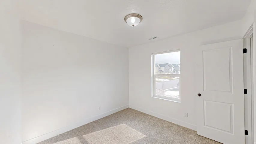 Room featuring neutral-toned carpet, white walls, and a single window with white trim