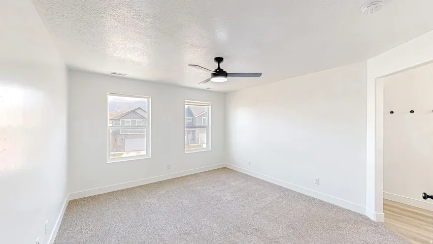 Spacious room featuring neutral carpet flooring and white walls