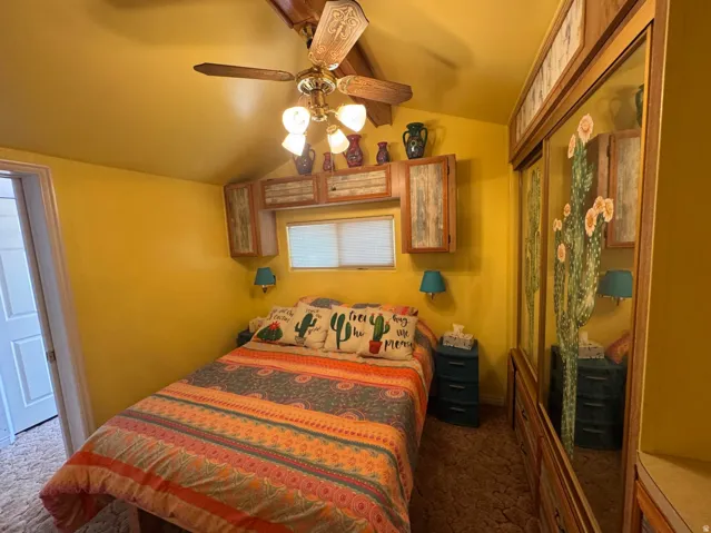 Room featuring a built-in wardrobe with mirrored doors, a window with blinds, and overhead cabinetry