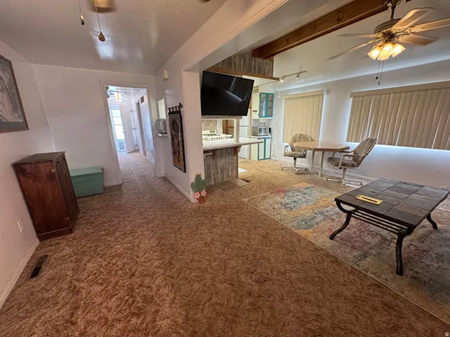 Open-concept living area featuring a decorative ceiling fan, track lighting, and a built-in breakfast bar