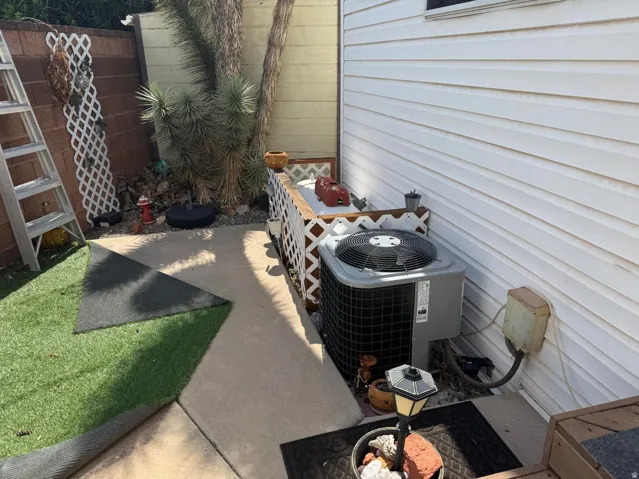 Concrete patio area with a white lattice fence, leading to a section of artificial turf