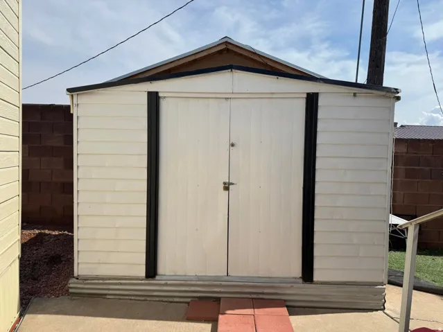 Freestanding storage shed featuring a gabled roof, double entry doors, horizontal siding, and a corrugated metal base