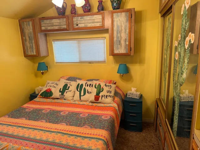 Bedroom featuring built-in cabinetry, window with blinds, and wall-mounted light fixtures