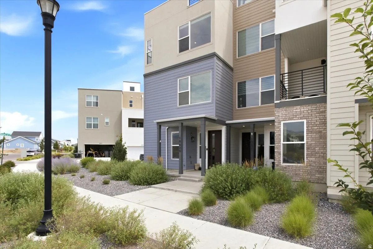 Contemporary multi-level exterior with varied siding, brick detailing, covered entry, and a second-story balcony with metal railing