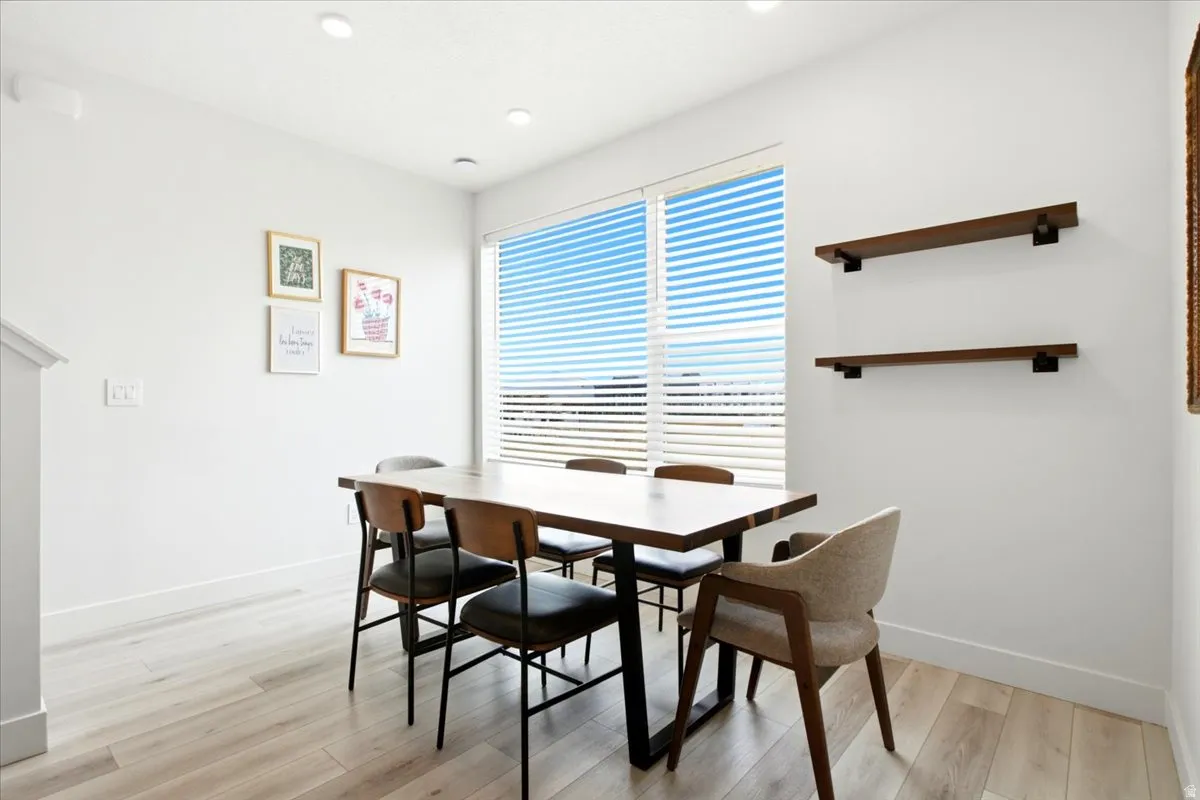Dining area featuring wood-finish flooring, recessed lighting, and a large window with horizontal blinds