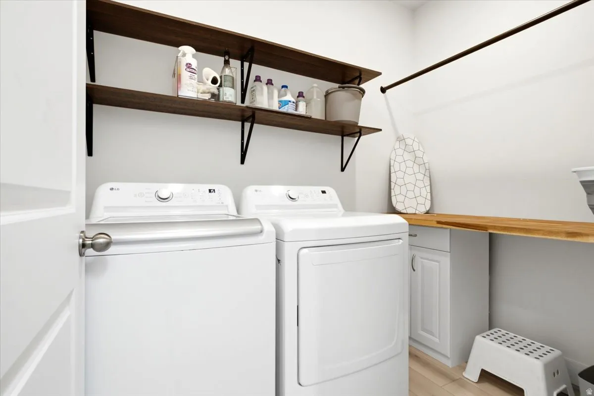 Dedicated laundry area featuring a white shaker-style base cabinet, a wood-finish countertop, and two floating wood-finish shelves with black metal brackets