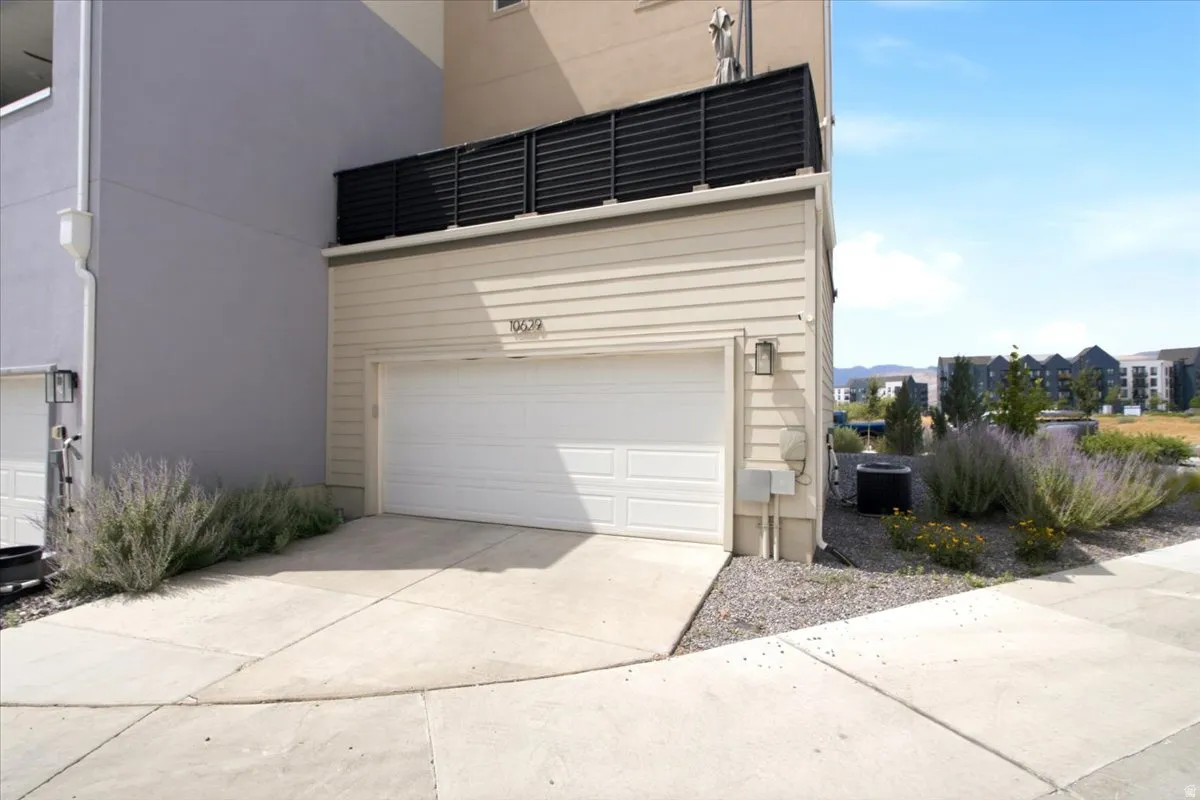 Attached single-car garage with a concrete driveway and vinyl siding