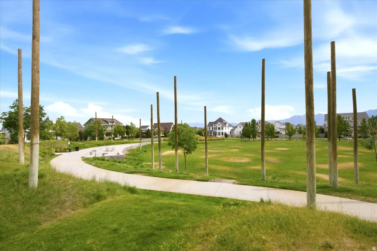 Expansive green space featuring a paved walking path, sculptural wood elements, and an amphitheater-style seating area