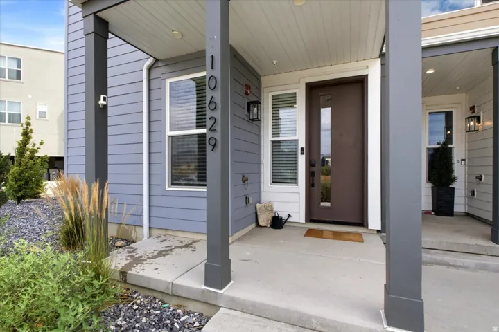 Contemporary exterior featuring a brown entry door with vertical glass insert, white window frames, and grey horizontal siding