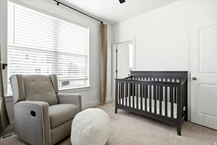 Carpeted room featuring a large window with horizontal blinds and full-height curtains, white painted walls, and white trim