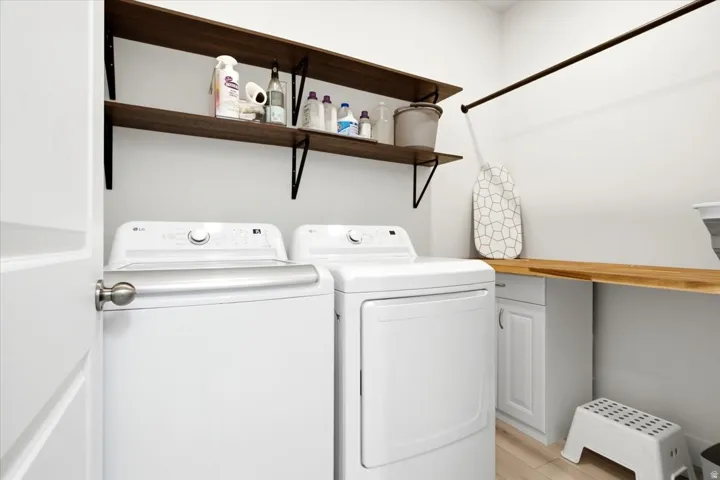 Dedicated laundry area featuring a white shaker-style base cabinet, a wood-finish countertop, and two floating wood-finish shelves with black metal brackets