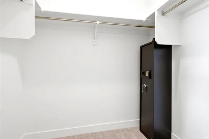 White closet system featuring upper shelving and a metal hanging rod