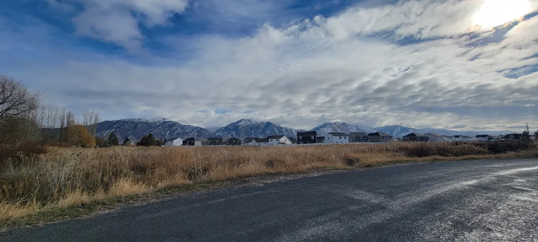 Expansive mountain range backdrop with distant residential structures