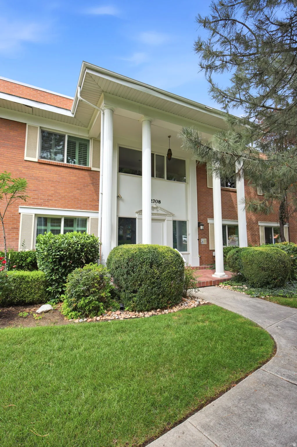 Brick exterior featuring a portico with four white columns and a central entrance