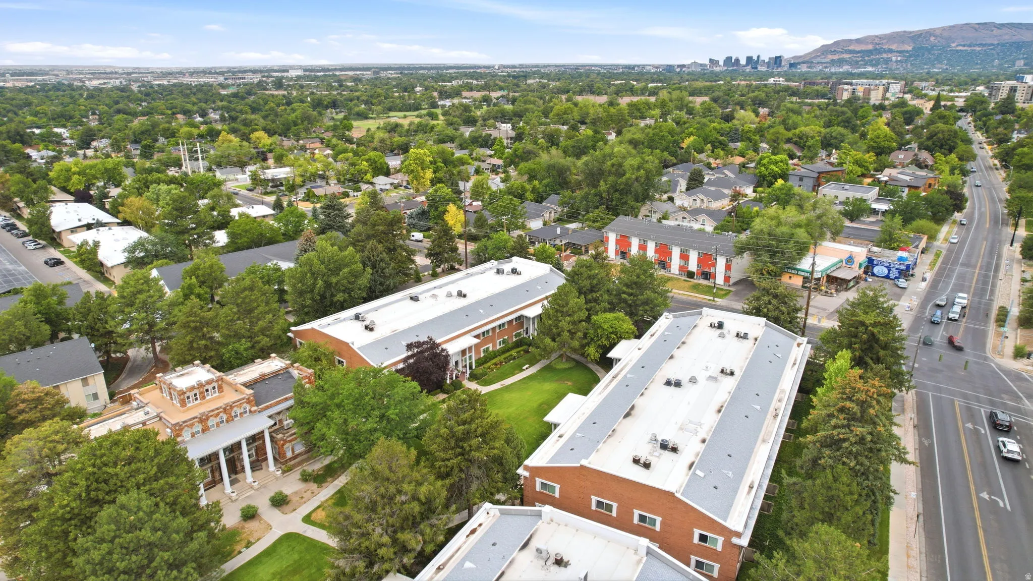 Campus-like setting featuring multiple multi-story brick buildings with white trim, green lawns, and mature trees