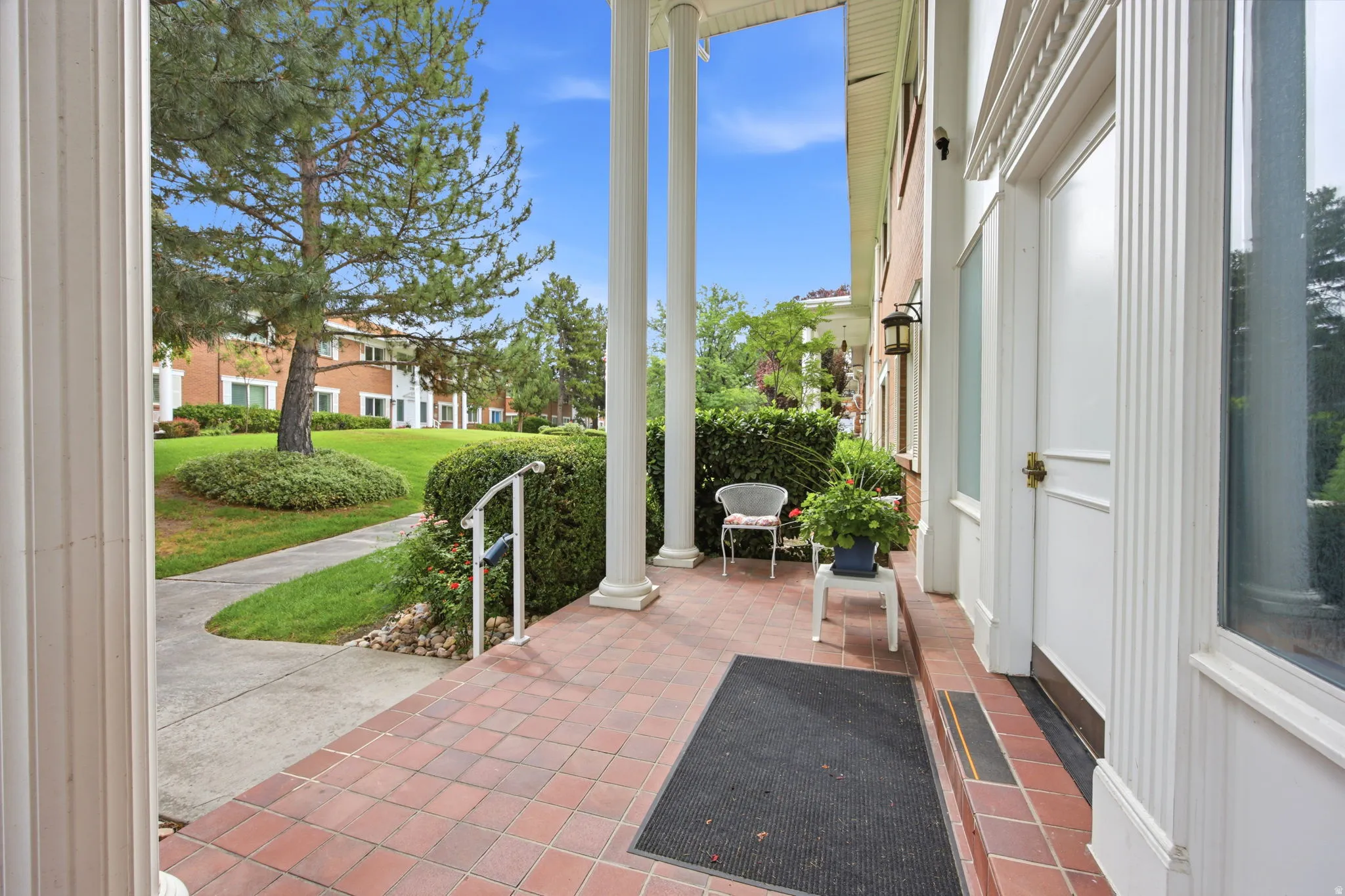 Entry porch featuring terracotta tile flooring and classic white columns
