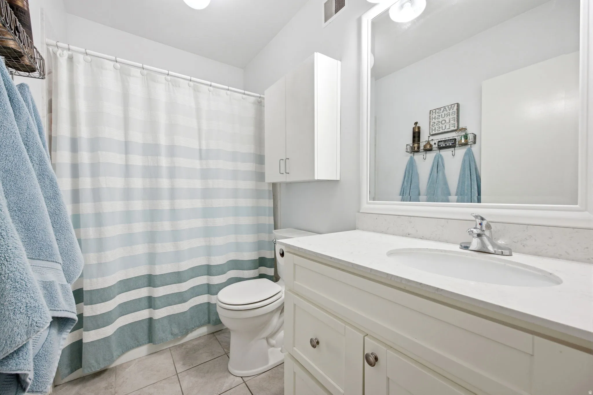 Bathroom featuring a white vanity with an integrated sink, polished chrome faucet, and a large framed mirror