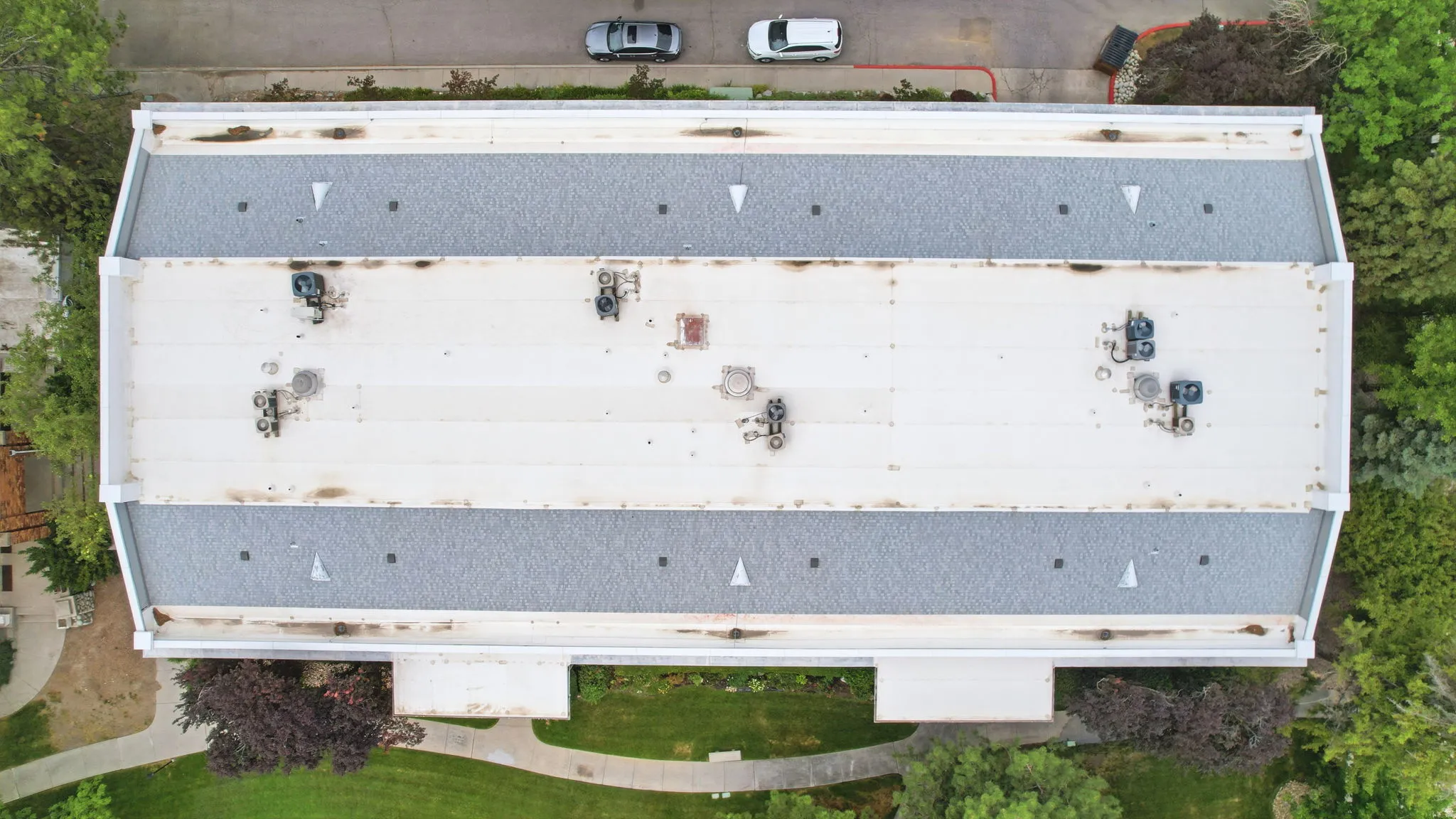 Building with a flat white roof and two gray shingle roof sections