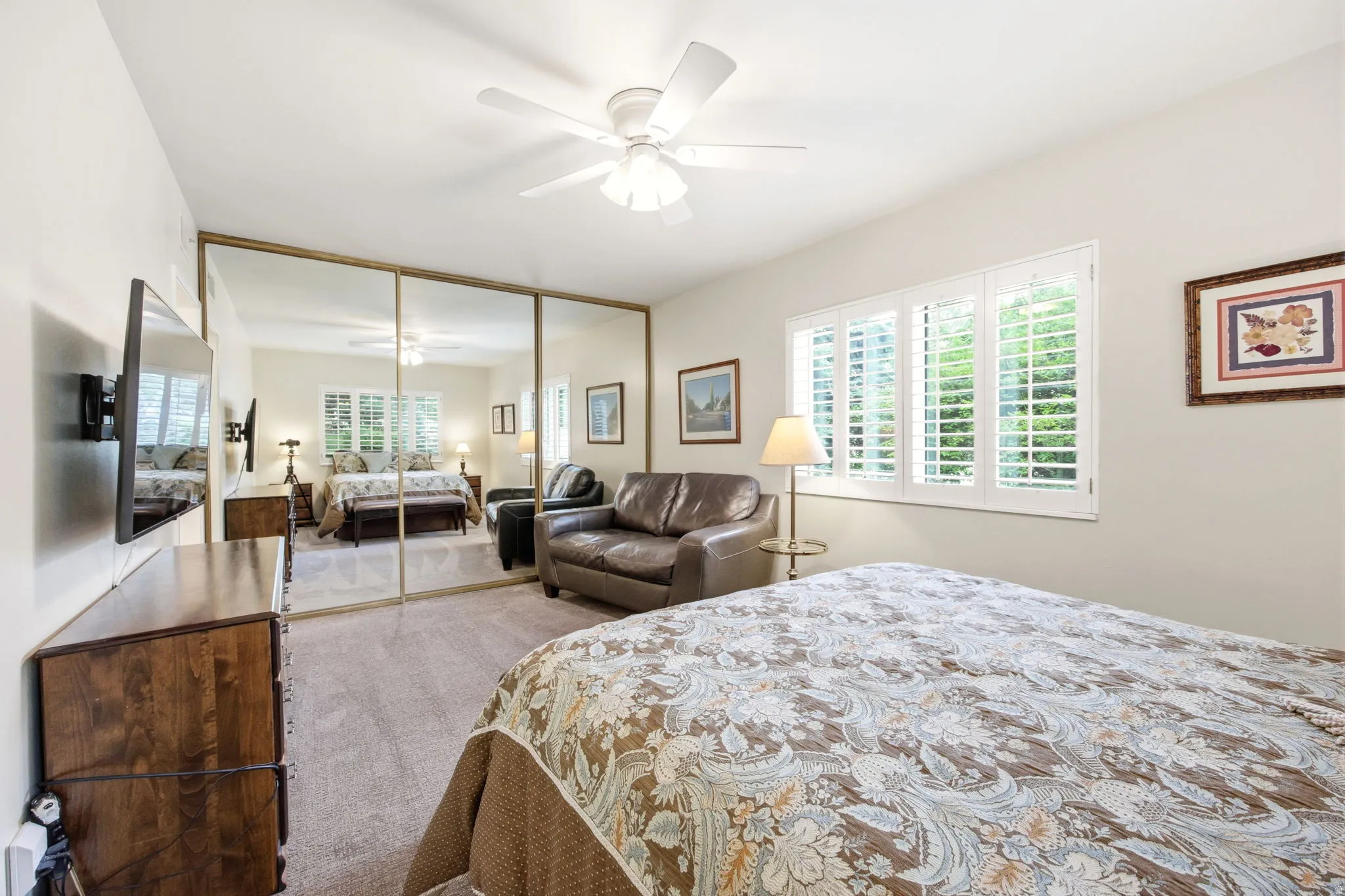 Mirrored wardrobe doors with gold-tone framing, plantation shutters, and a ceiling fan with integrated lighting