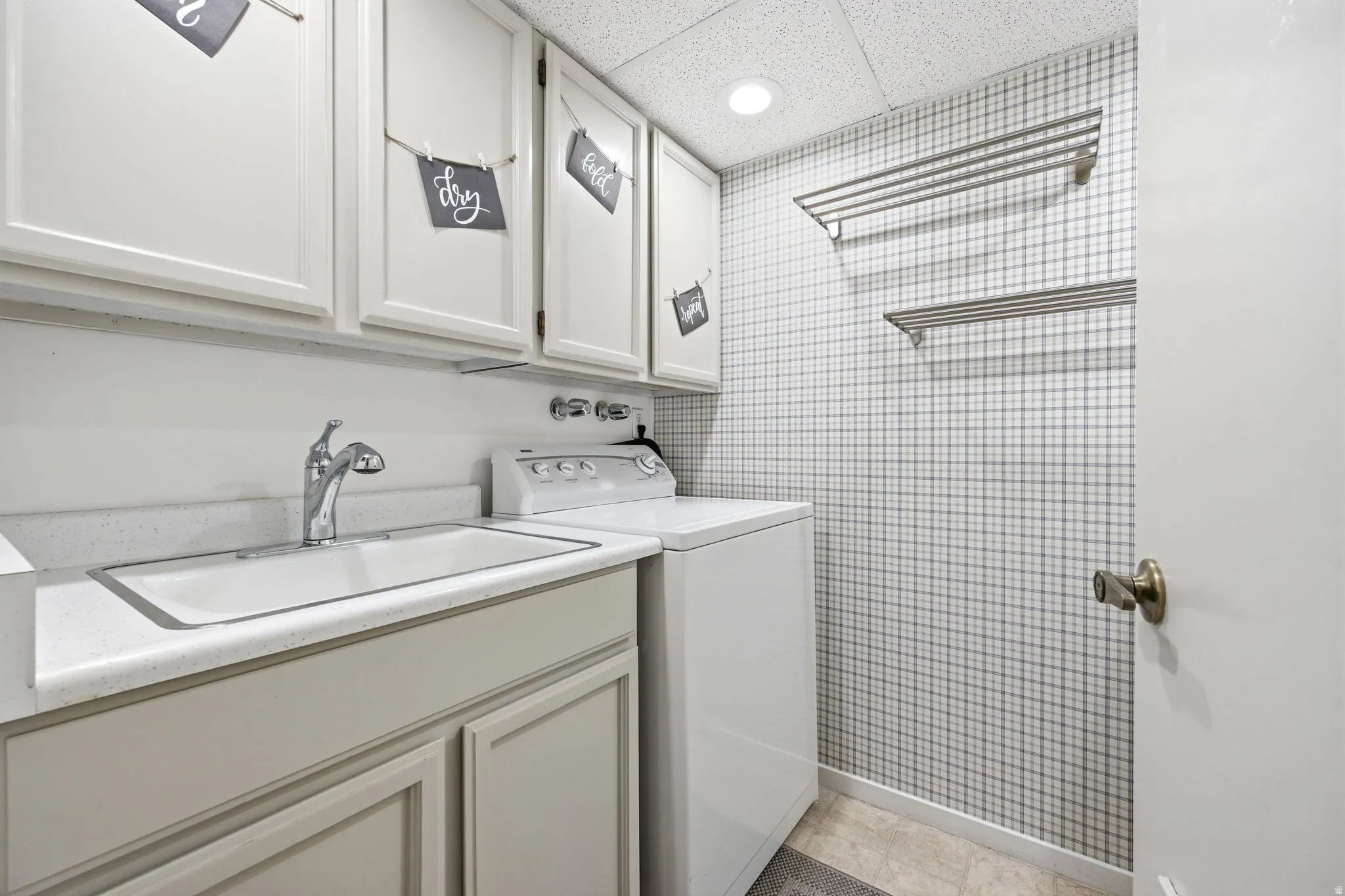 Utility sink with chrome faucet, complemented by white upper cabinetry and a light-toned countertop