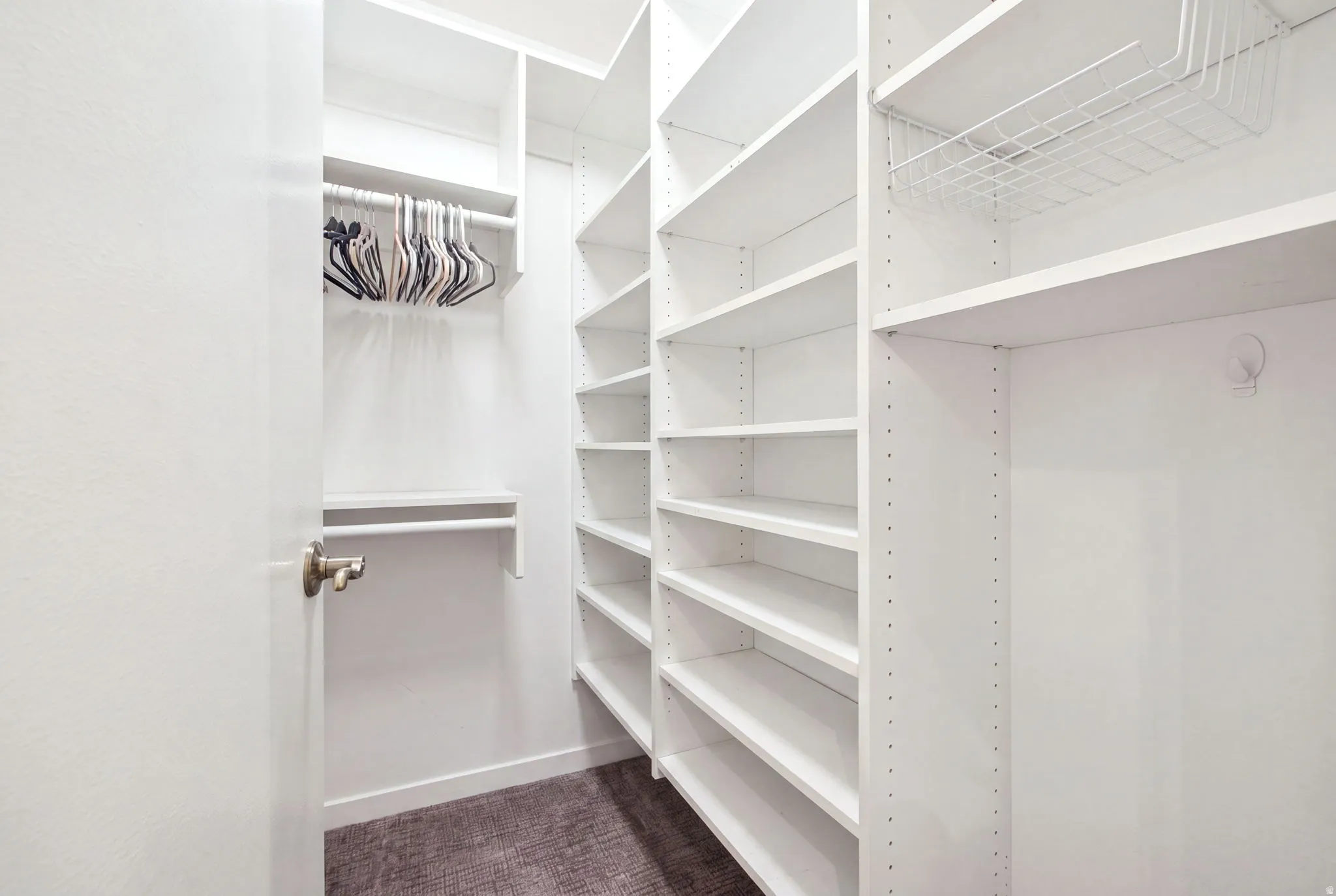 Walk-in closet featuring white shelving, multiple hanging rods, and a wire storage basket