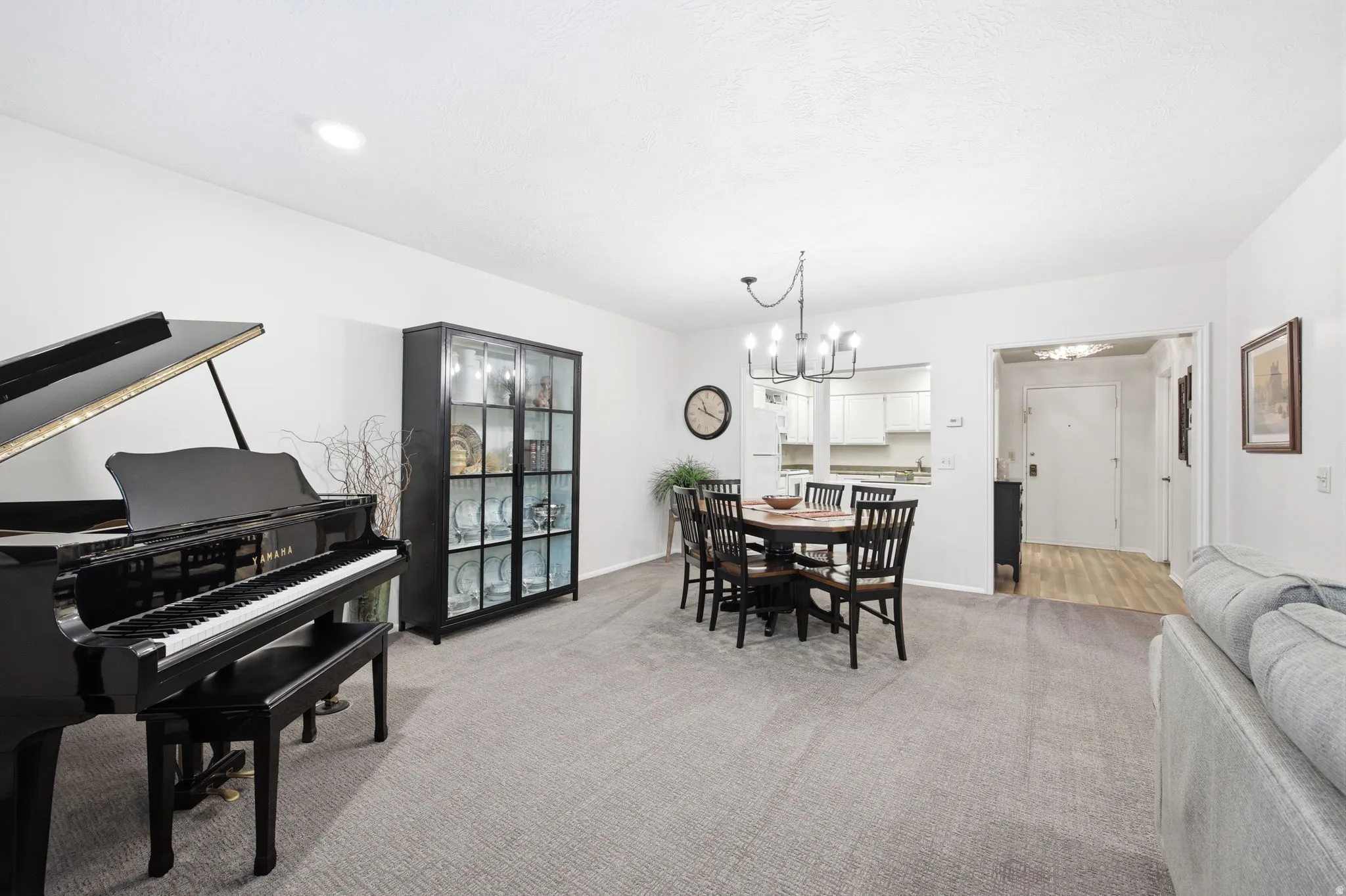 Open-concept living space featuring neutral carpeting, recessed lighting, and a contemporary chandelier