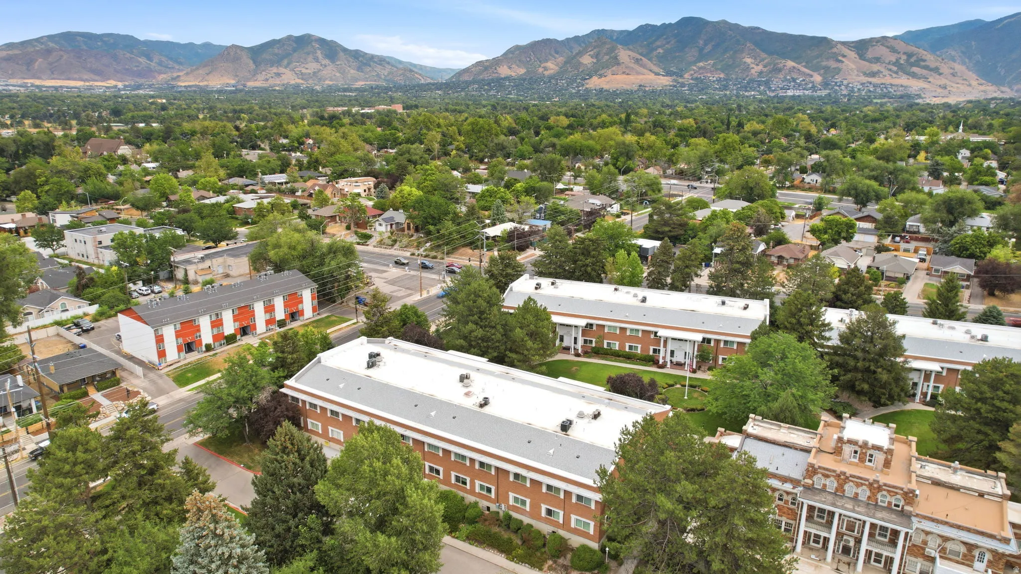 Expansive aerial perspective showcasing multiple properties amidst mature trees and a structured community layout