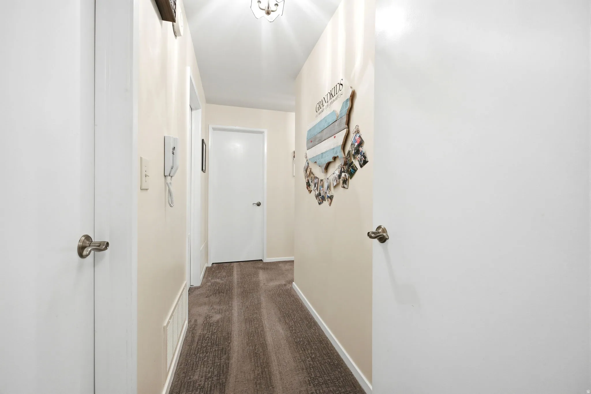Hallway featuring neutral wall paint, white trim, and a textured carpeted floor