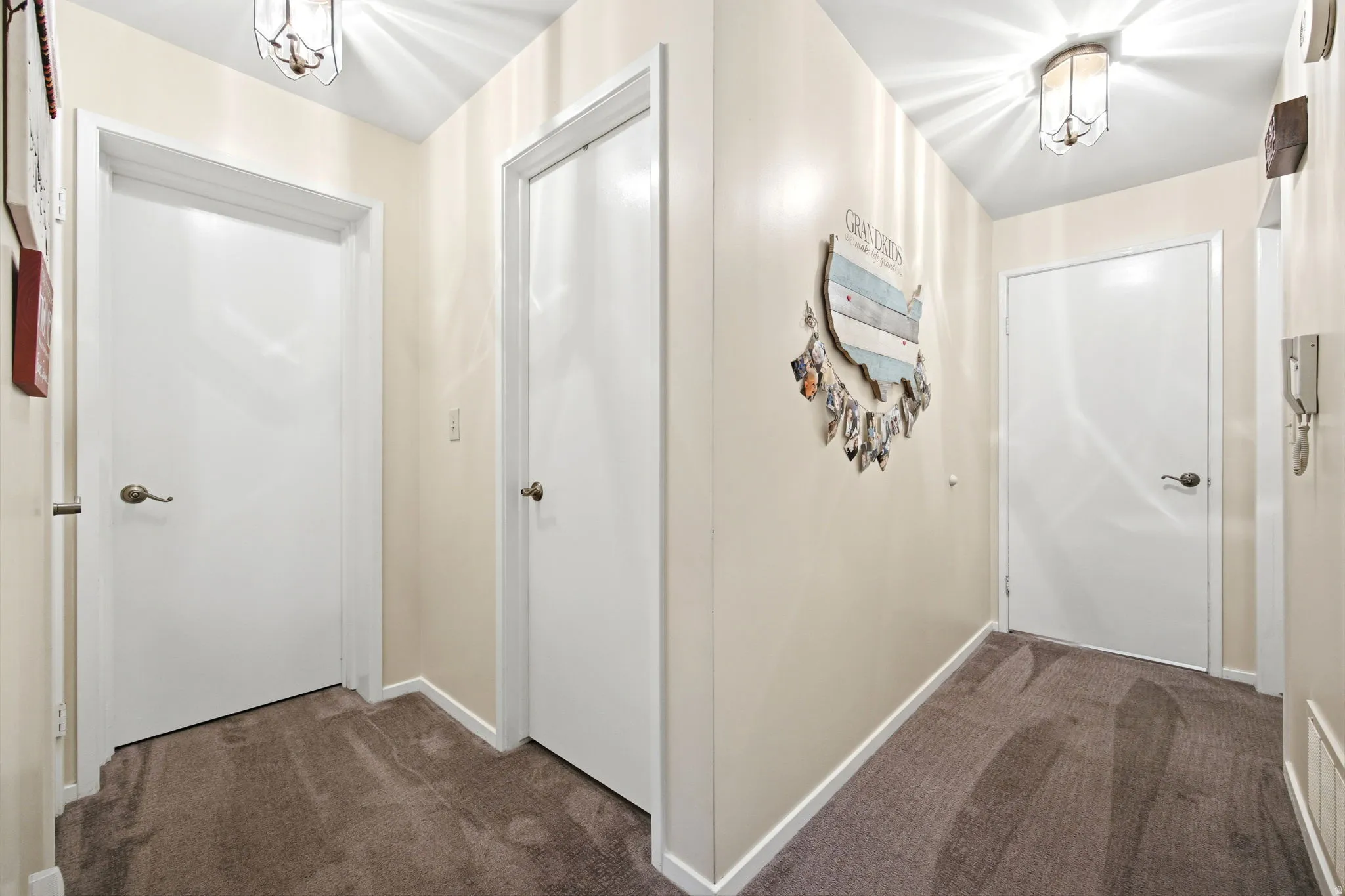 Hallway featuring light neutral wall paint, white trim, and brown carpet flooring