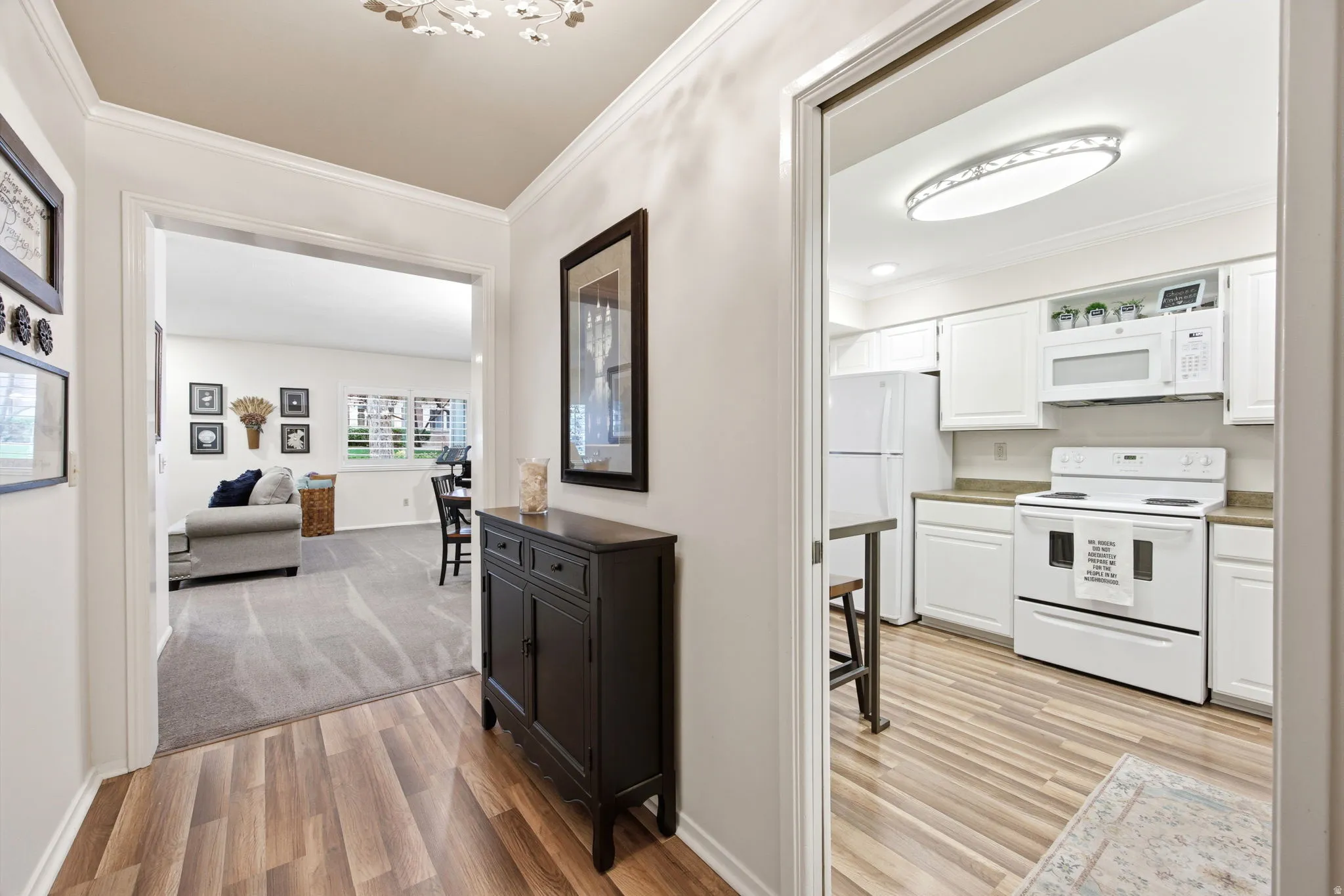 Welcoming entryway featuring wood-finish flooring, crown molding, and a decorative ceiling light fixture