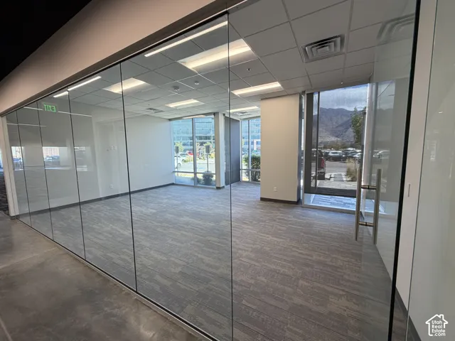 Glass panel wall, recessed lighting, carpet flooring, large windows, mountain backdrop