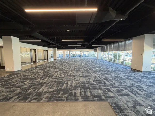 Expansive open-plan interior featuring abstract-patterned carpeting and concrete flooring