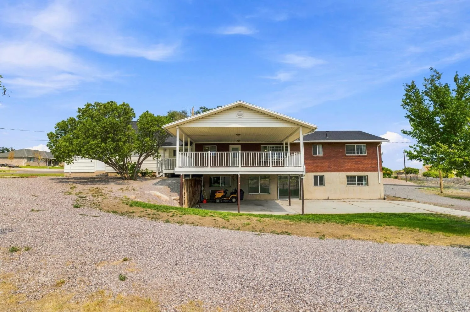 Two-story home featuring a covered upper-level balcony and a covered lower-level patio