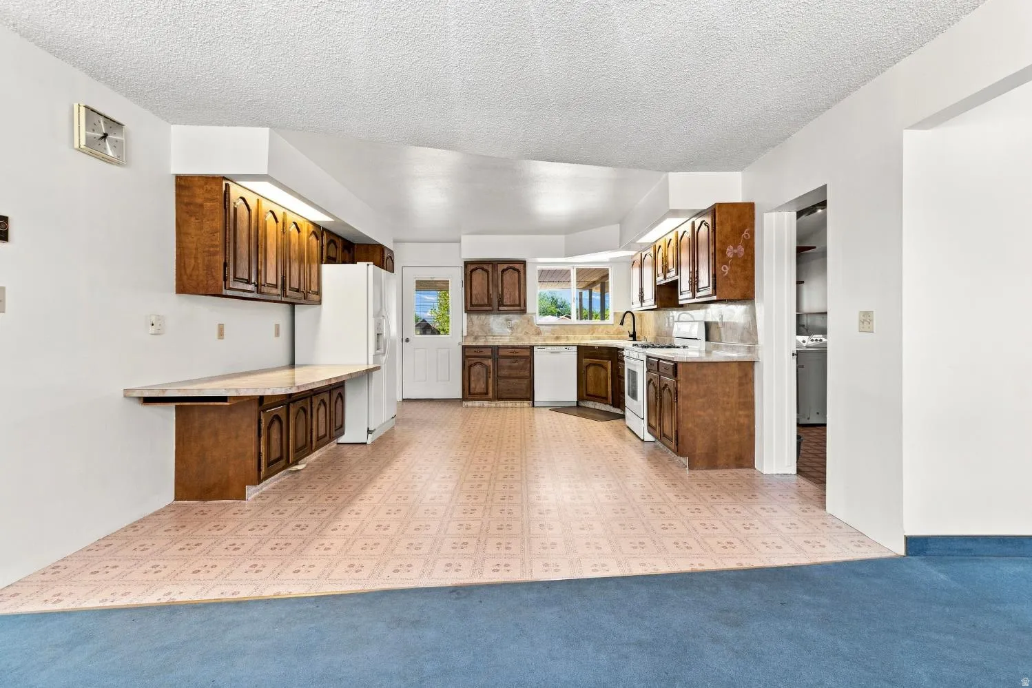 Kitchen featuring wood cabinetry, stone-look countertops, and white appliances