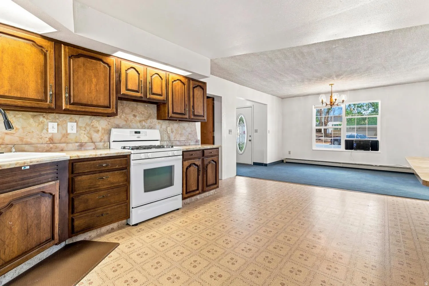 Kitchen space featuring wood cabinetry, white appliances, and patterned tile-look flooring