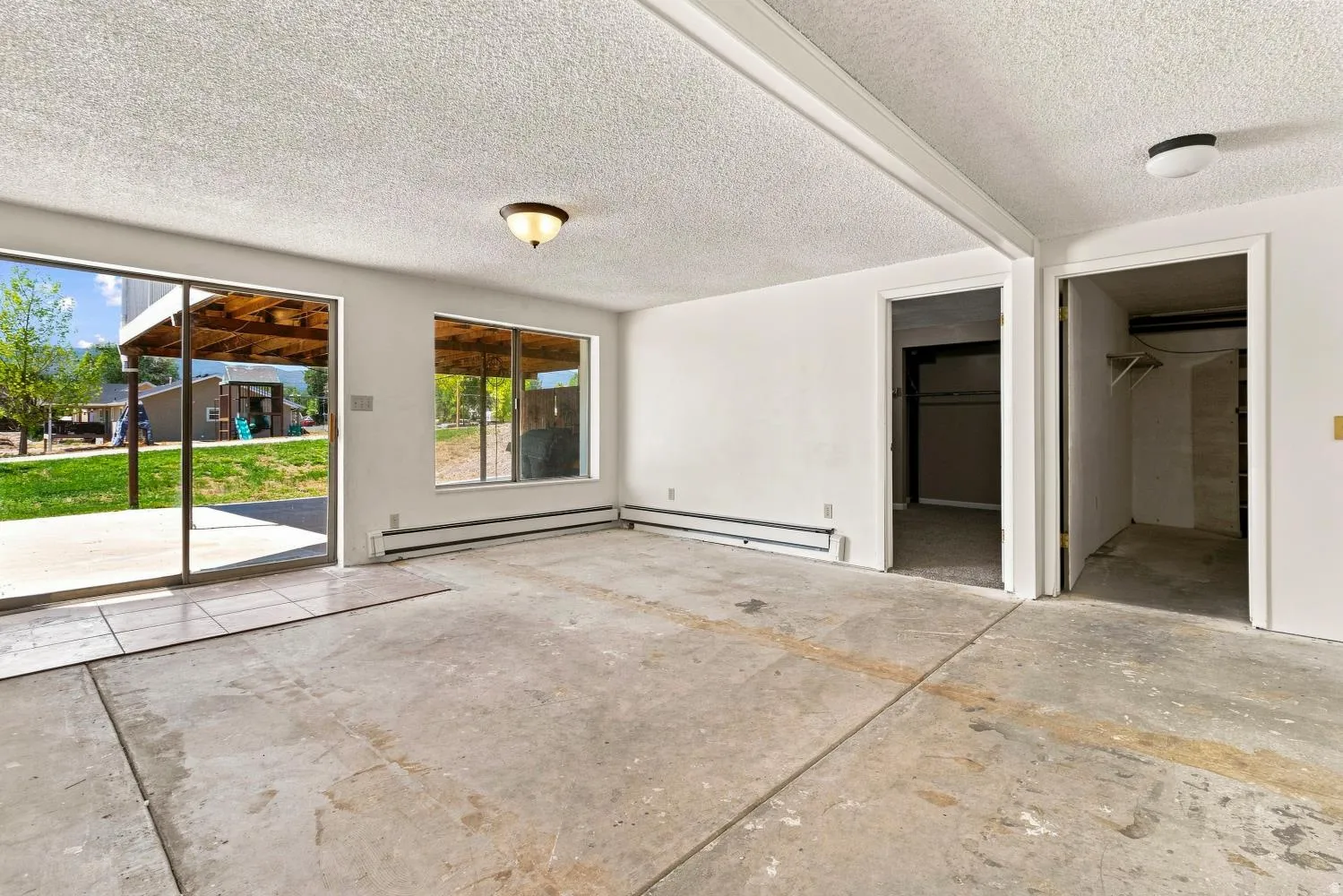 Spacious interior room featuring concrete flooring and textured ceiling