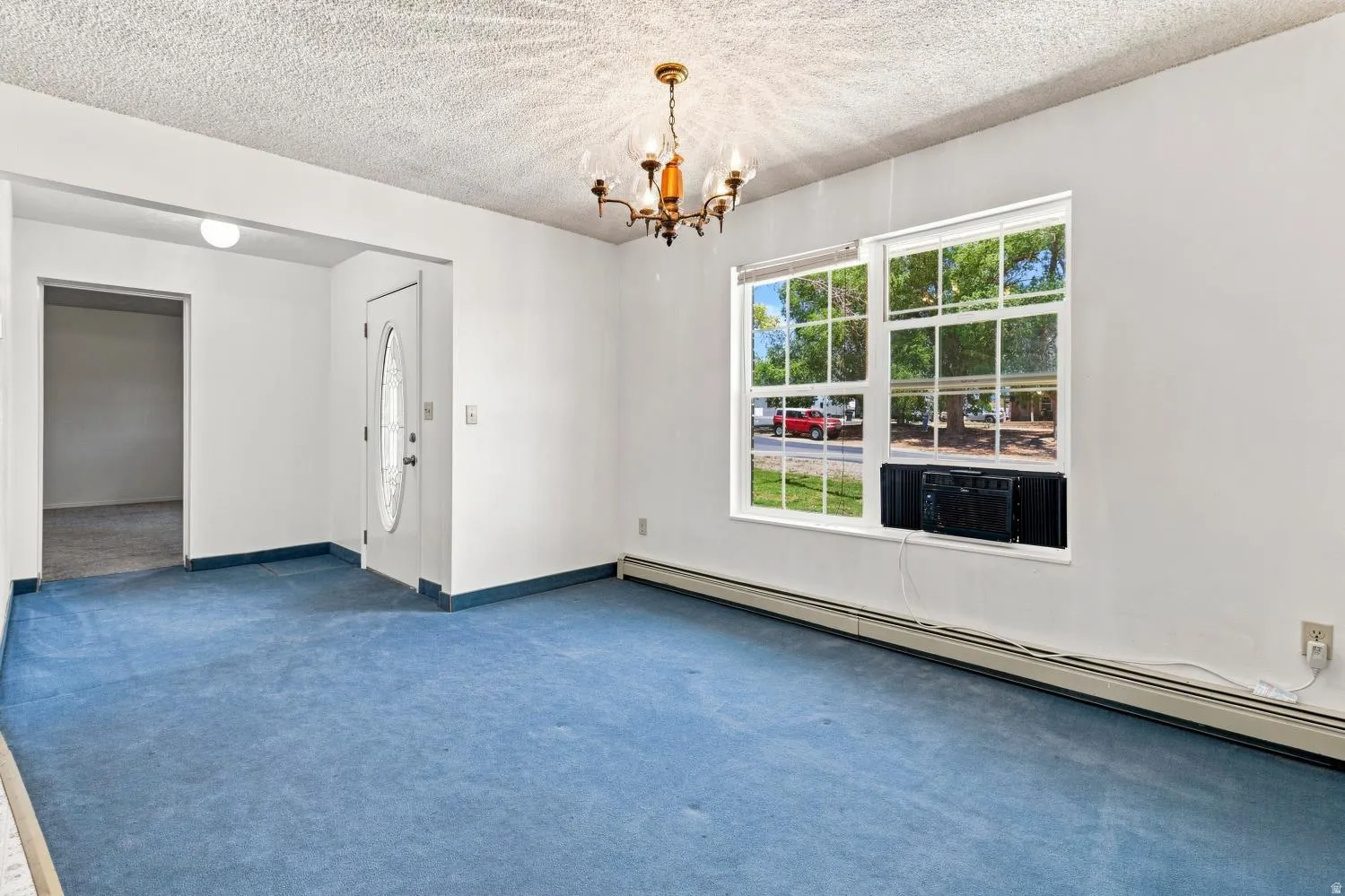 Interior space featuring blue carpeting, white walls, and a textured ceiling