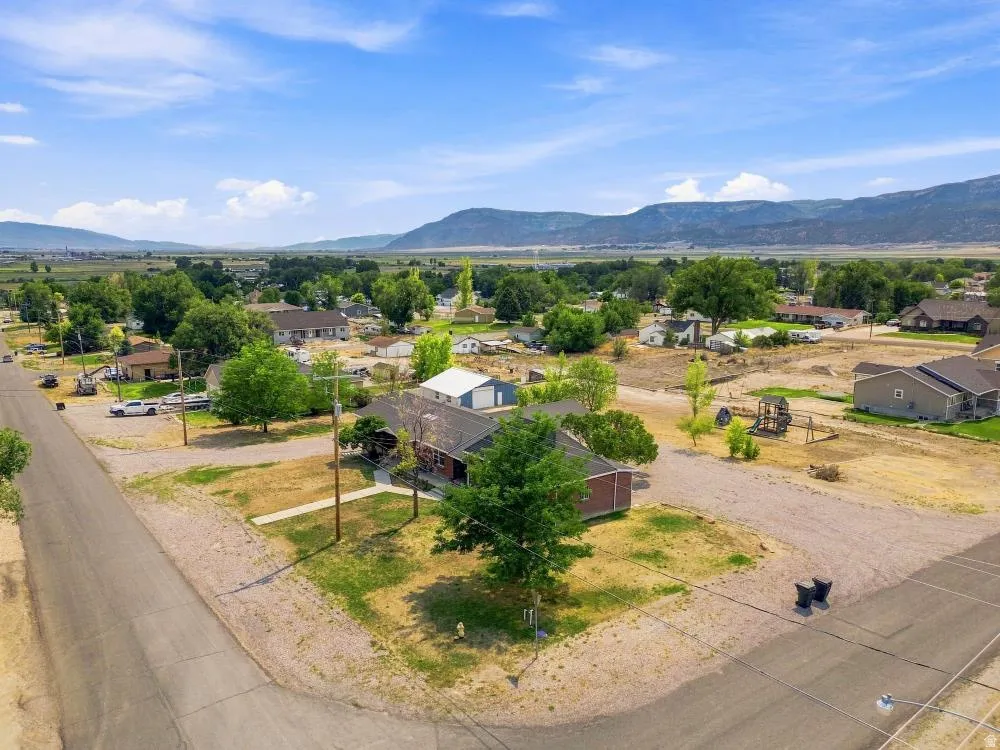 Expansive corner lot featuring a traditional-style residence with a dark roof and a detached garage/shop structure