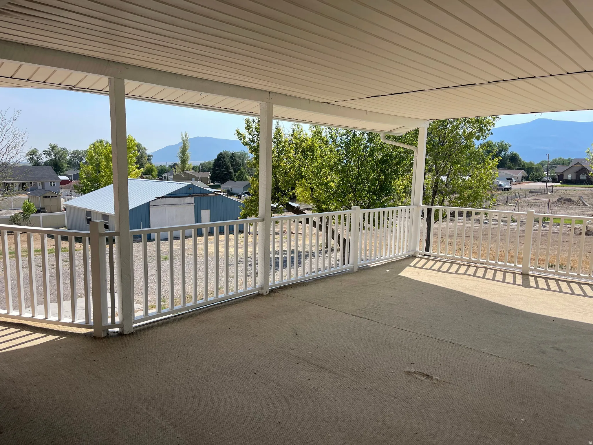 Covered outdoor patio space with a concrete surface and white railing