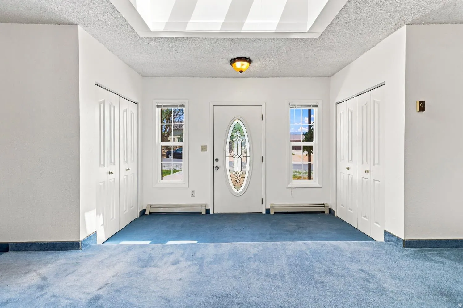 Entryway featuring a decorative oval-insert front door, two side windows, and a flush mount ceiling light