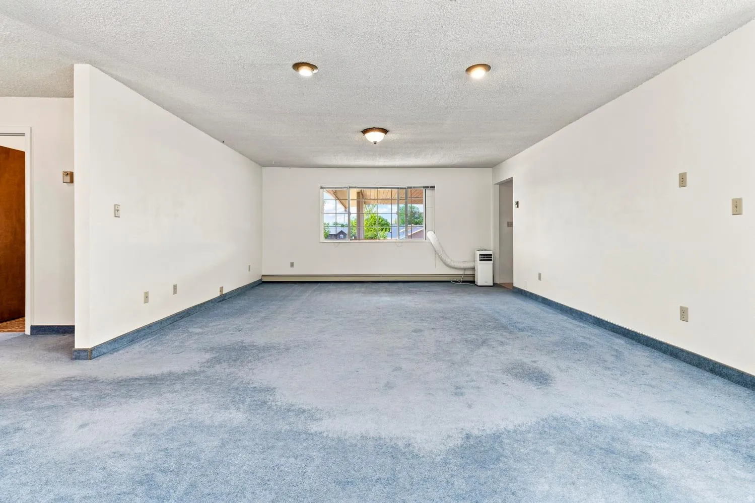 Expansive interior space featuring a window, textured ceiling, recessed lighting, and wall-to-wall carpeting