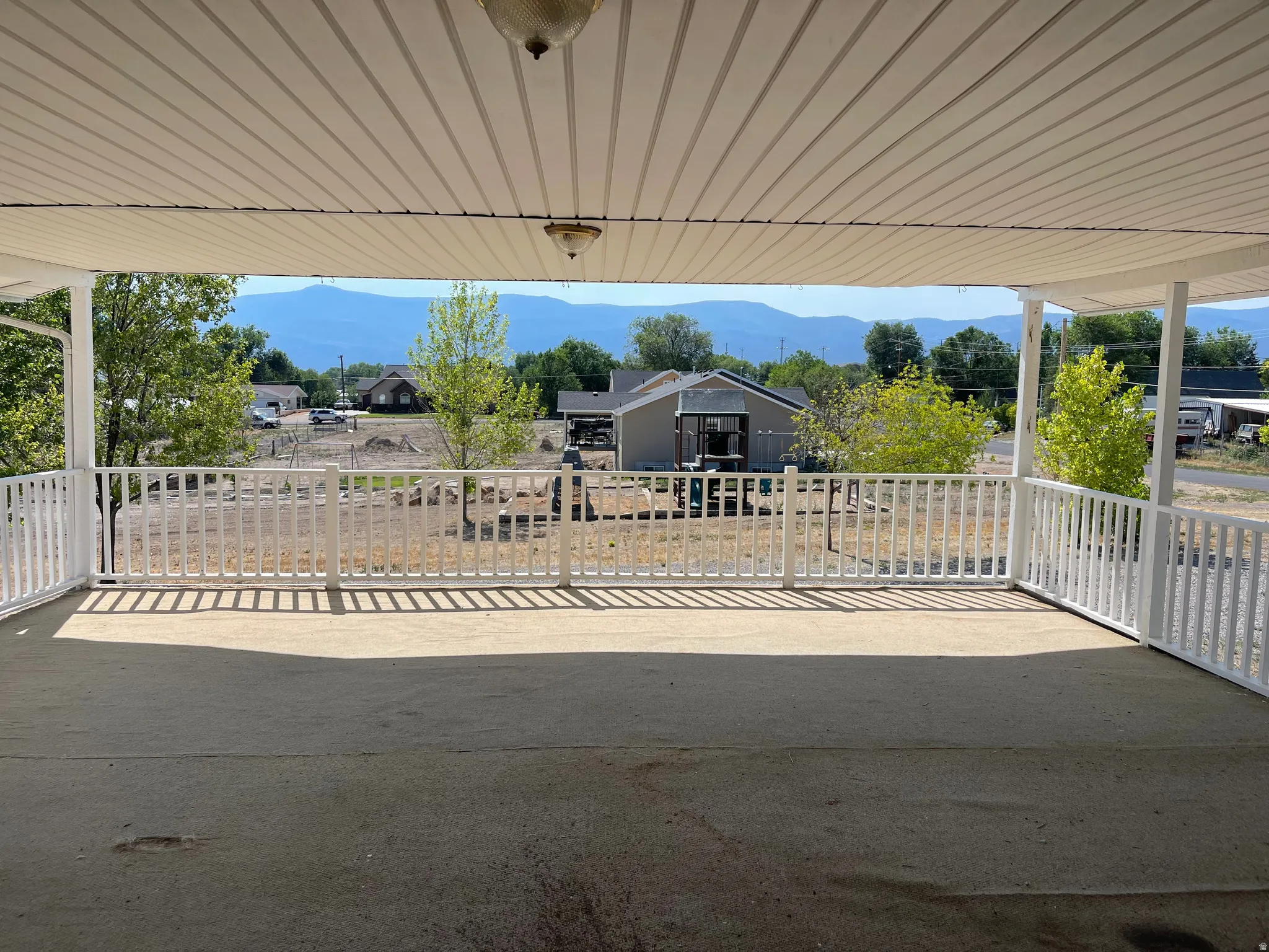 Expansive covered patio featuring a concrete surface and white railing