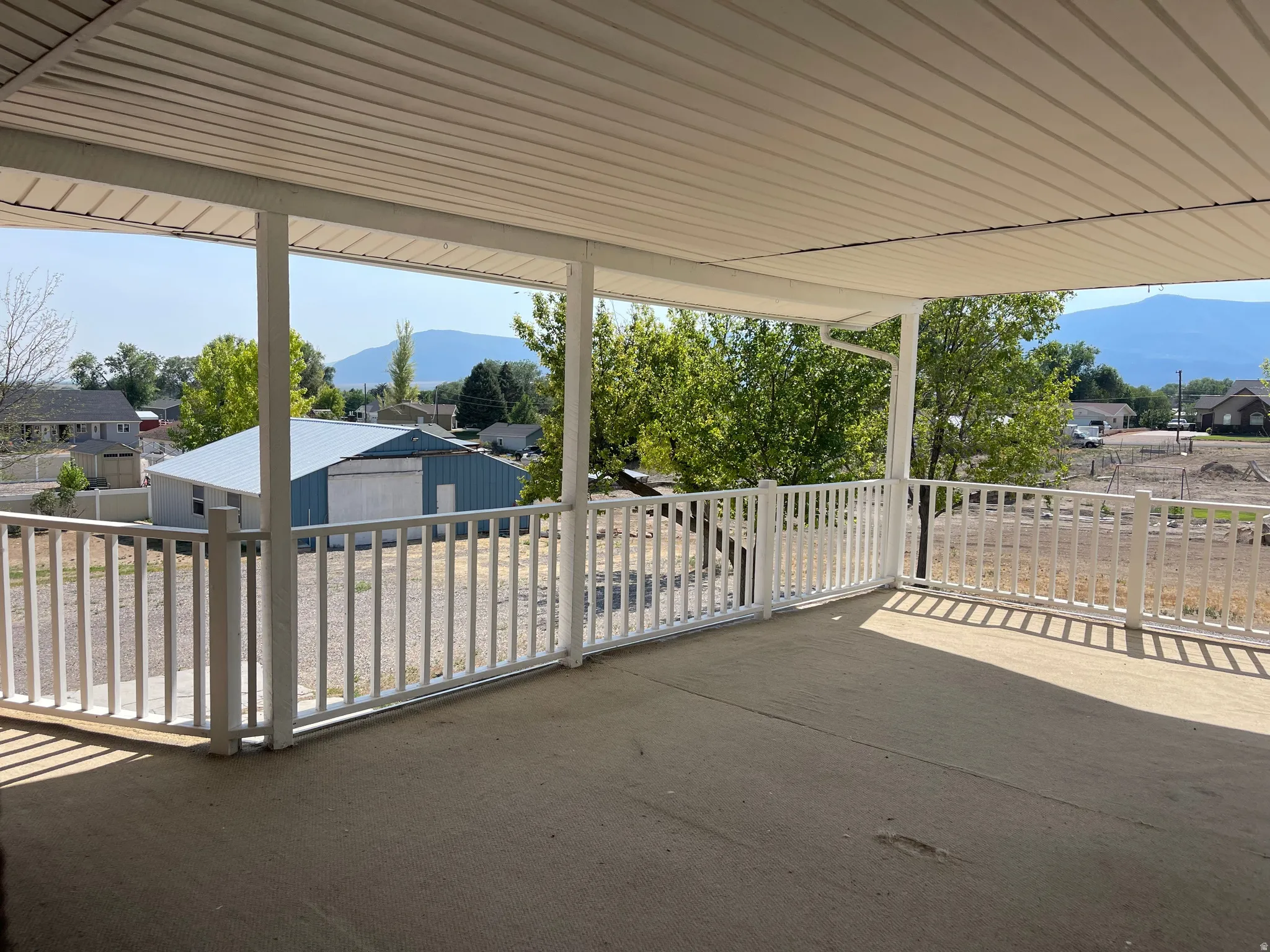 Covered concrete patio with white railing and mountain backdrop