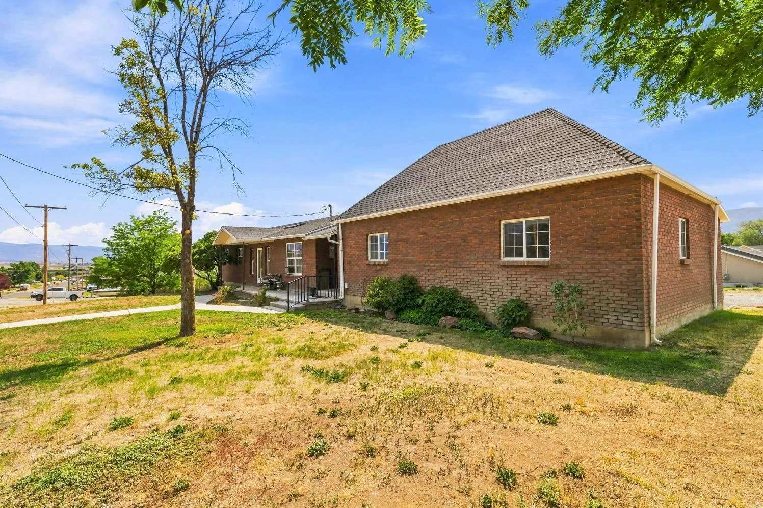 Brick exterior with a dark shingle roof, featuring white-framed windows and a covered front porch