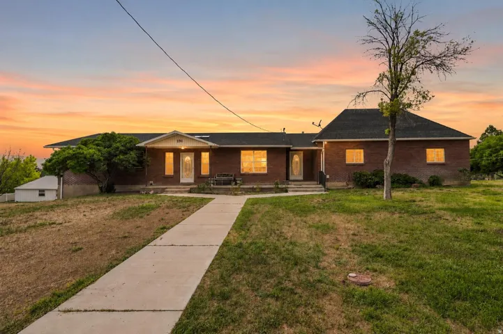 Brick exterior property featuring a prominent concrete walkway, covered entryway, and mature landscaping