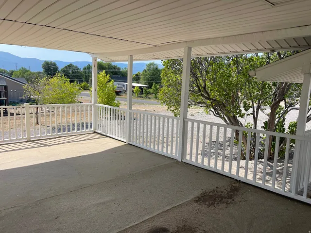 Covered porch with concrete flooring and white railing